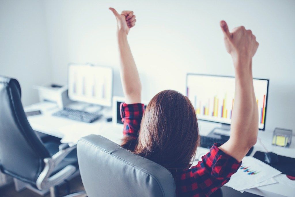 женщина сидит за компьютером, показывая два больших пальца вверх