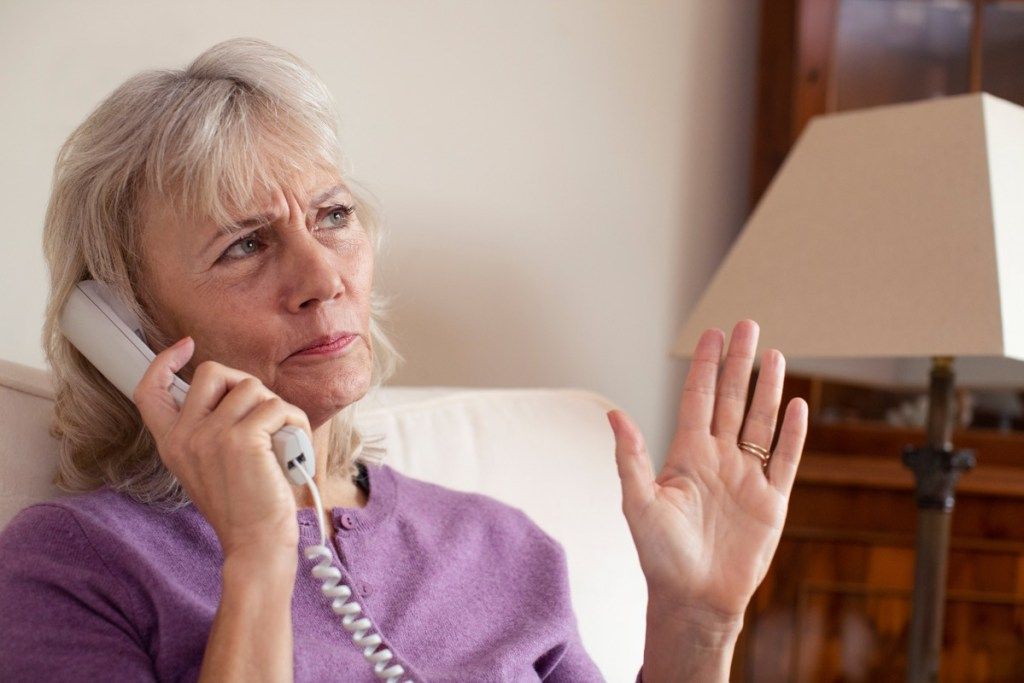 Starejša ženska, ki doma prejema neželen telefonski klic