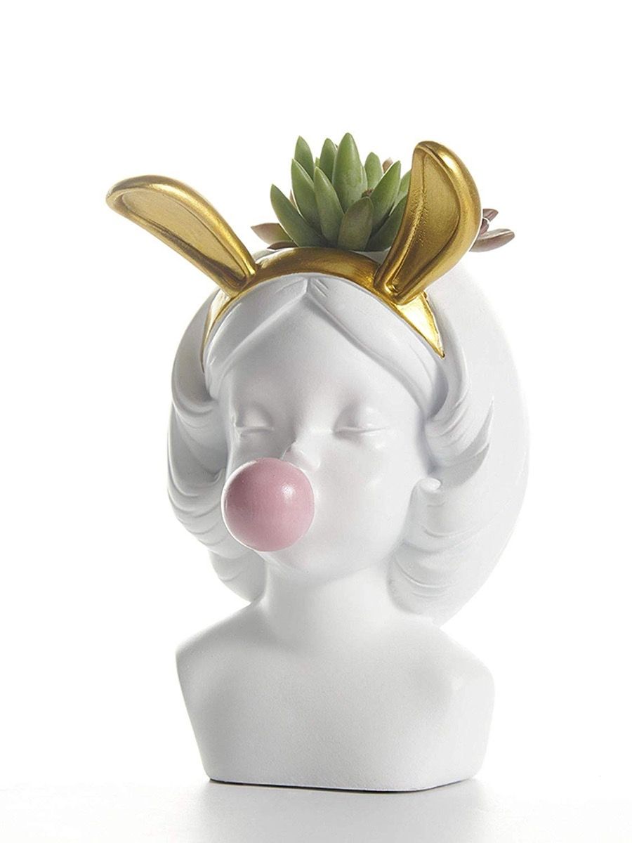 balta keramikas vāze ar meiteni zelta zaķa ausīs pūš burbuļgumiju