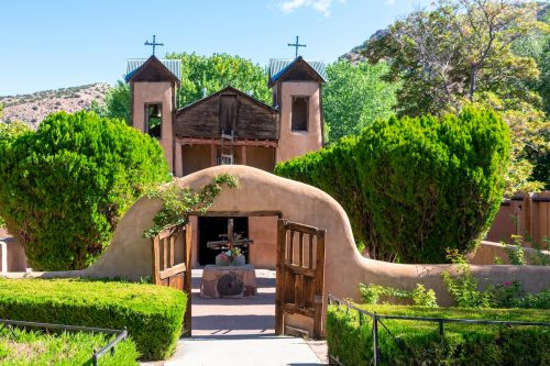   Įėjimas į istorinę adobe bažnyčią El Santuario de Chimayo Chimayo mieste, Naujojoje Meksikoje su kalnais fone