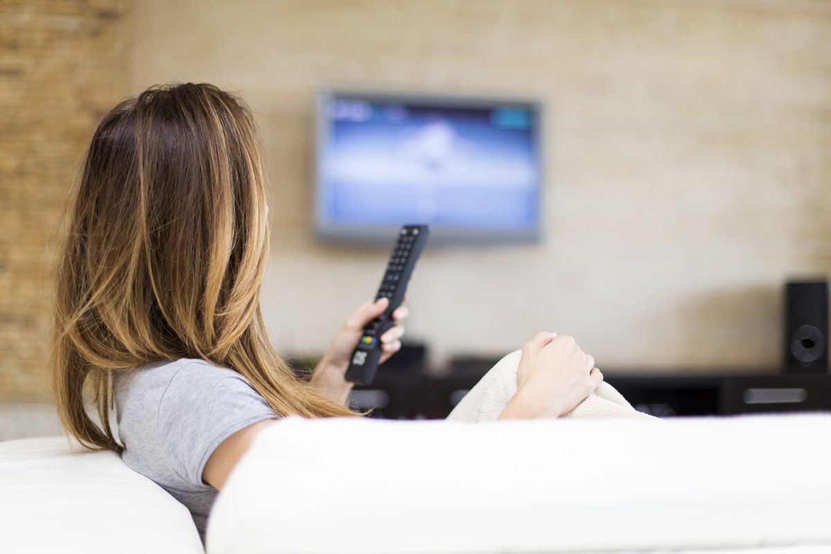Femeie care se uită la televizor pe canapea