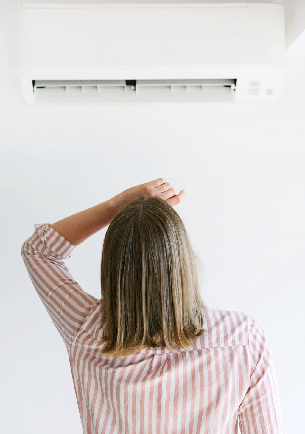 Vrouw met airconditioner manieren om de rekening van de airconditioning te verlagen