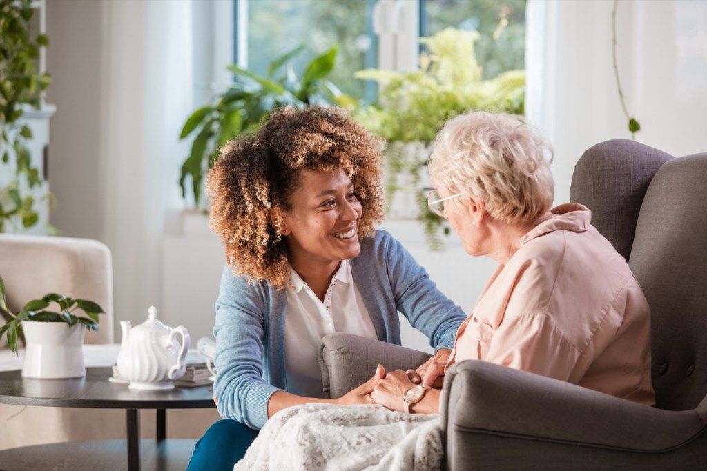nainen puhuu vanhusten kanssa hoitokodissa