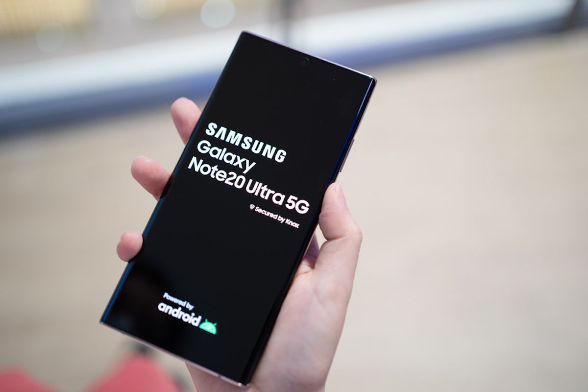 Изглед на ръка, която държи Samsung Galaxy Note20 Ultra 5G Mystic Bronze Color със стартиращ екран