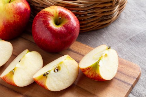   Manzanas rojas maduras y manzanas cortadas en la tabla de cortar