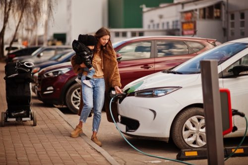   mujer cargando auto electrico