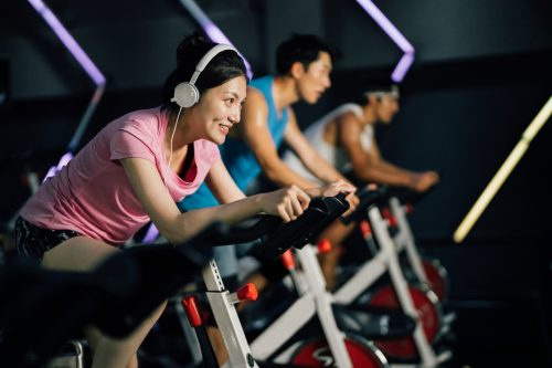   Mujer joven asiática en bicicleta en una bicicleta estática en el gimnasio.