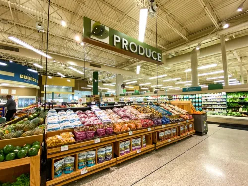   Maisto prekių parduotuvės šviežių produktų koridorius su spalvingais šviežiais vaisiais ir daržovėmis, kuriuos vartotojai gali įsigyti.