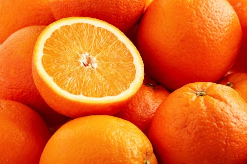   ערימה של תפוזים טריים עם חצי פרוסה אחת.