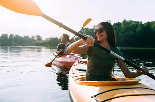   Hermosa pareja joven en kayak en el lago juntos y sonriendo