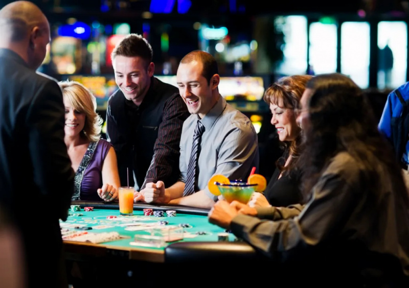   En grupp människor som dricker vid ett kortbord i ett kasino