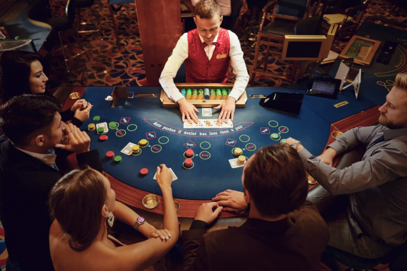   Un repartidor de cartes en una taula de blackjack o pòquer plena de gent