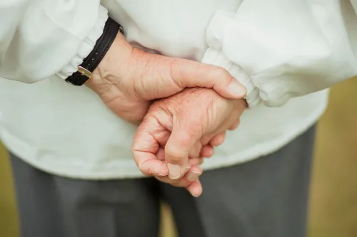   En närbild av en äldre man's hands behind his back, holding them together.