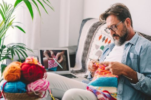   homme tricotant avec tutoriel en ligne