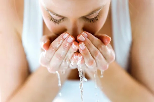   顔に水しぶきをかける女性