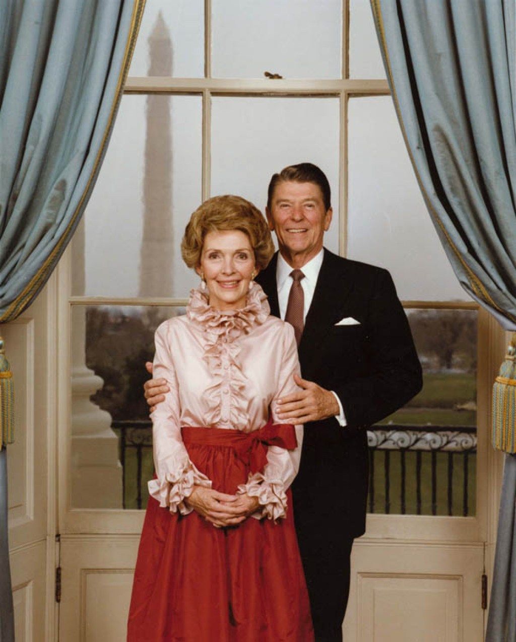 El presidente Reagan y la Sra. Reagan posan en el Salón Azul para su retrato oficial, Nancy vistiendo una camisa con volantes, moda de los años 80