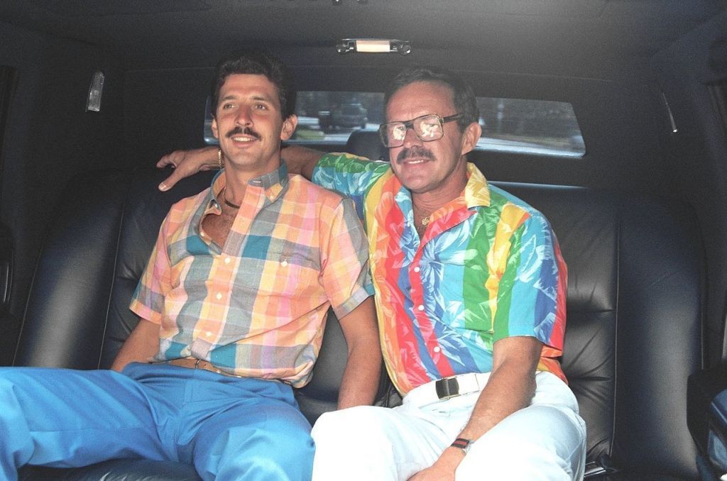 двама мъже в задната част на колата, единият с казални очила, мода от 1980-те