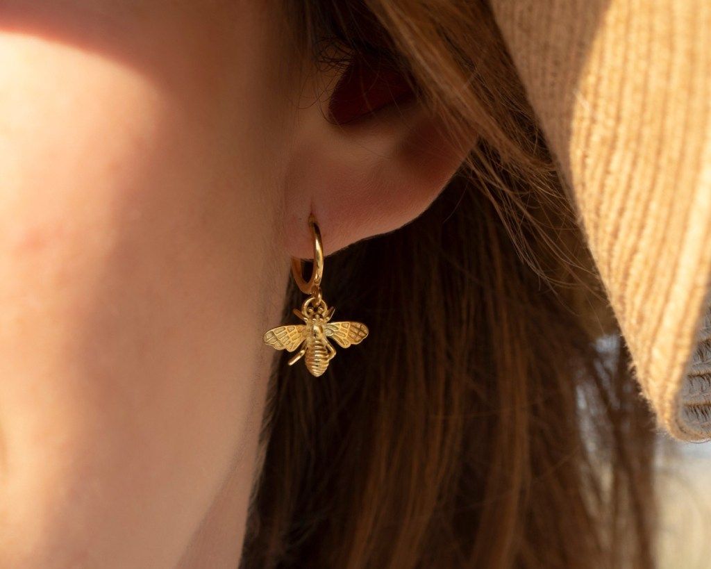 naine kannab kuldseid mesilaste kõrvarõngaid, Etsy ehteid