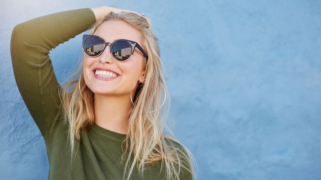mujer sonriente y con gafas de sol, cómo vestirse mayores de 40