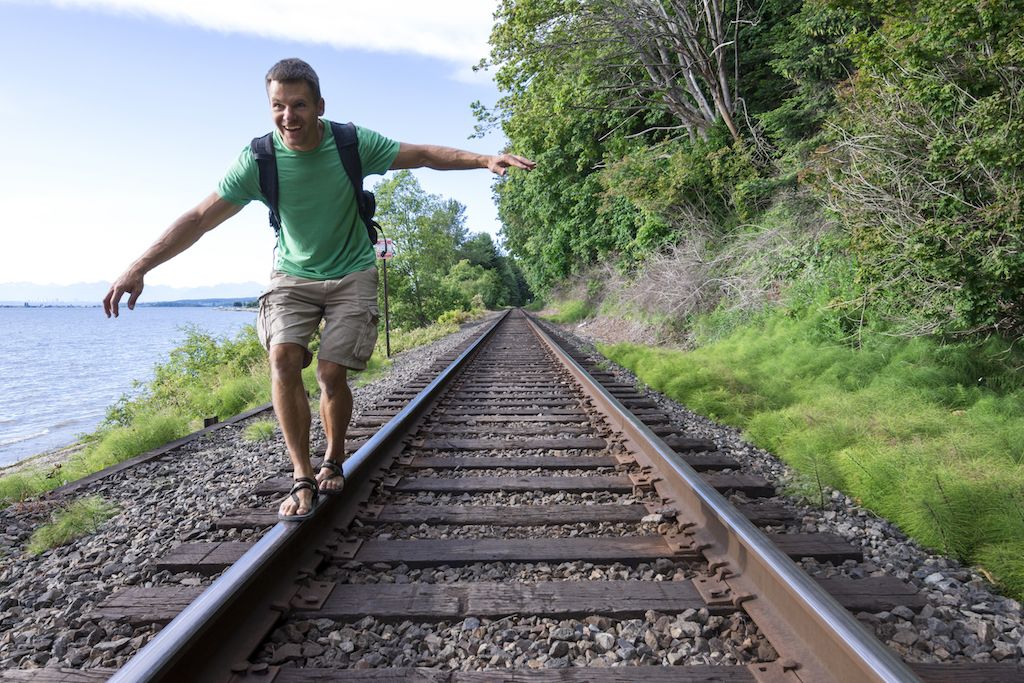 Hombre caminando sobre las vías del tren en pantalones cortos de carga, cómo vestirse a más de 40