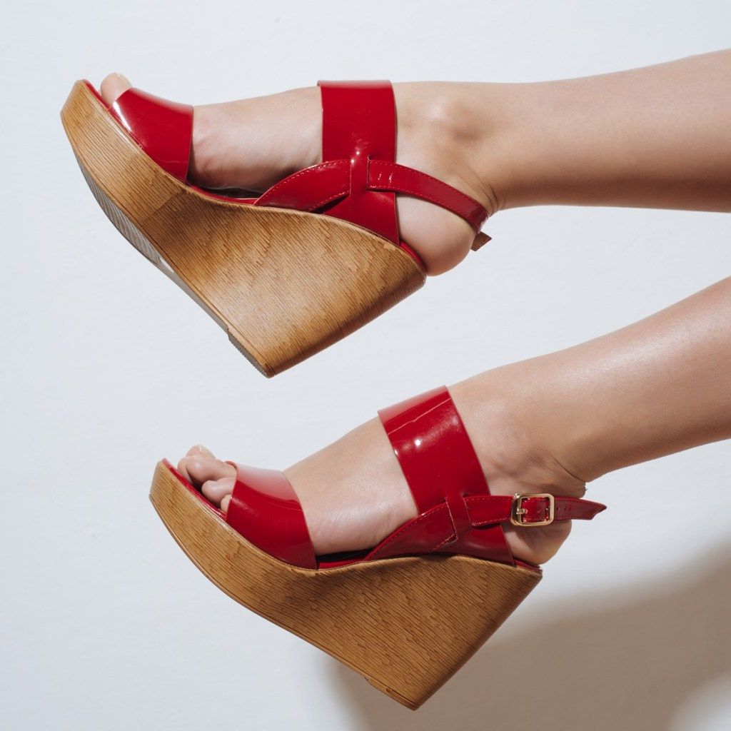Hermosas piernas femeninas en sandalias rojas en una cuña