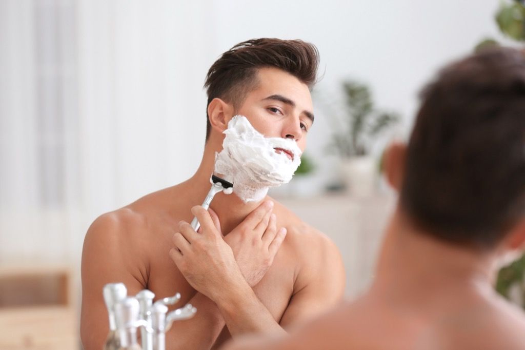 мъж, бръснещ крем за бръснене пред огледало