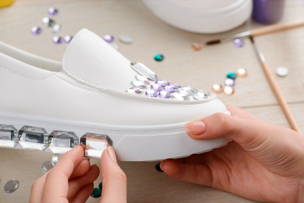 एक किशोर लड़की जूते पर पर्ची की एक सफेद जोड़ी को रोशन करती है