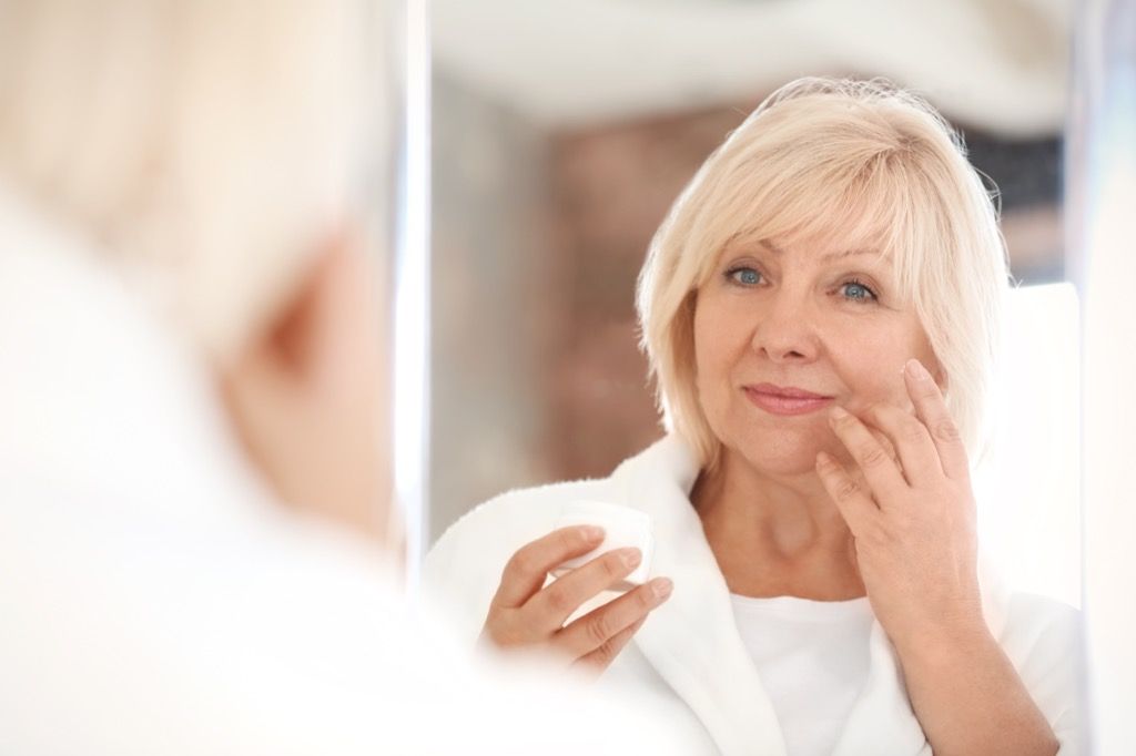 Mujer de mediana edad mirando en un espejo, maquillaje para mujeres mayores