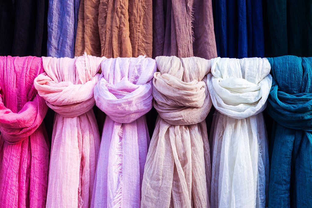 bufandas rosadas y moradas colgadas en un perchero: cómo vestirse más de 50