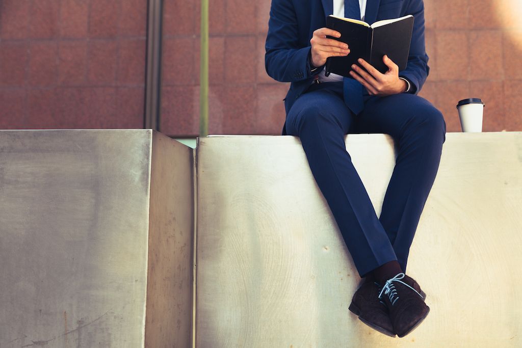 vīrietis uz apmales un lasa grāmatu uzvalkā - kā ģērbties virs 50 gadiem