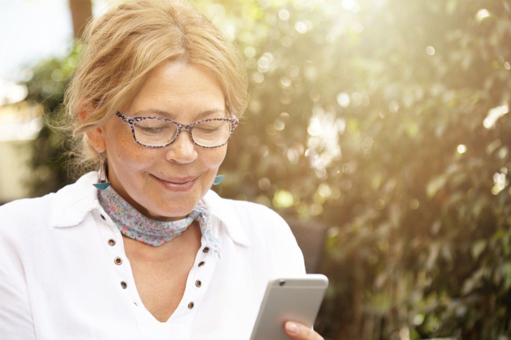 mujer mayor mirando su teléfono - cómo vestirse más de 50