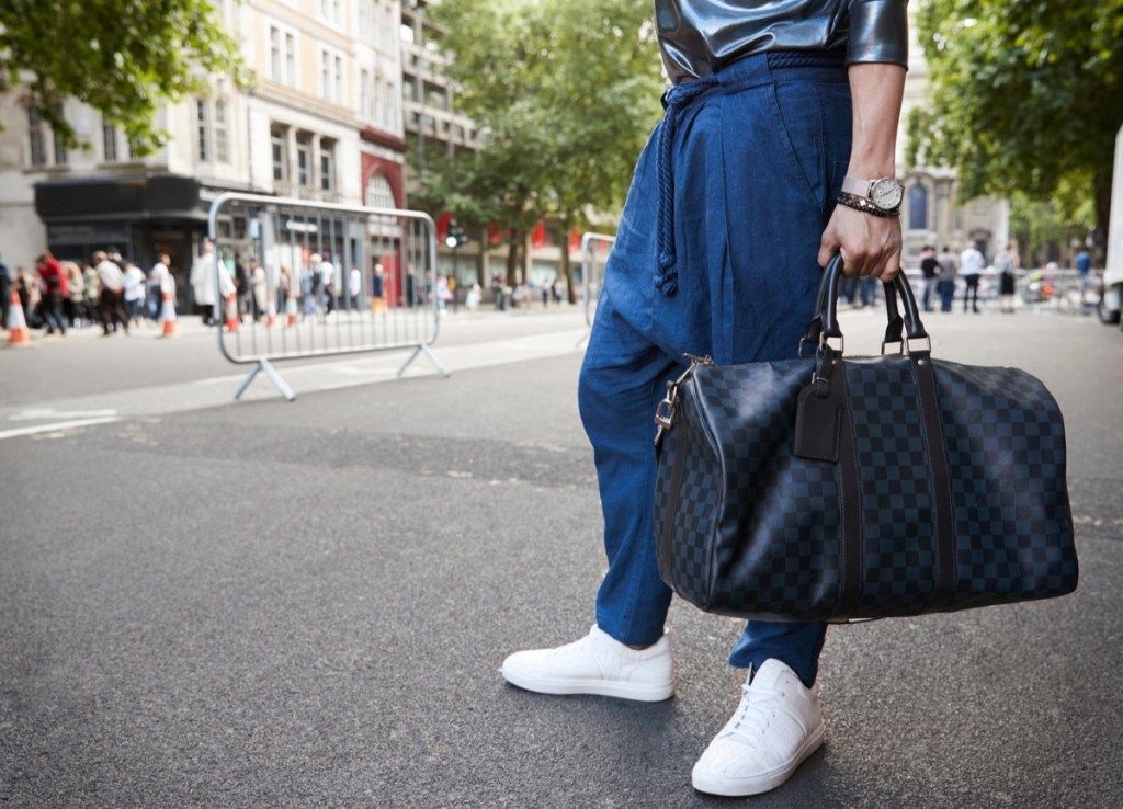 Mann, der Drop-Crotch-Sweats mit einer Gucci-Reisetasche trägt