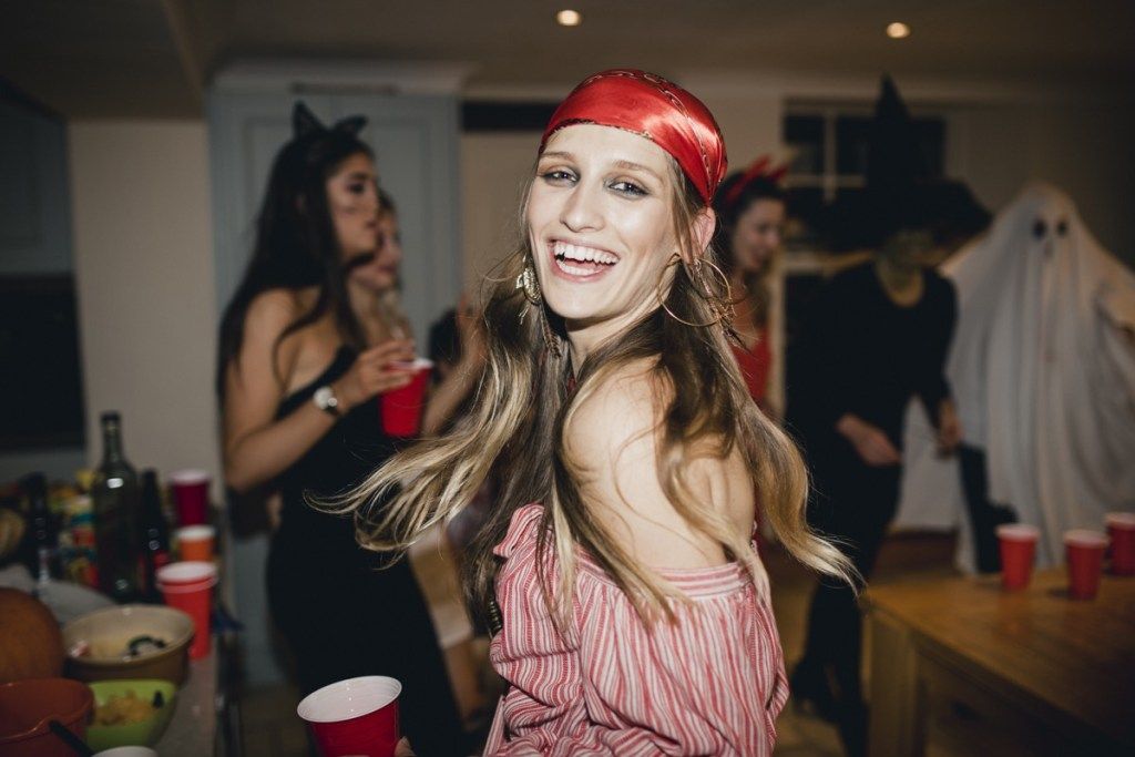 ہالووین پارٹی میں سمندری ڈاکو کے لباس پہنے ہوئے عورت ہنستے ہوئے اور ناچتے ہوئے کیمرہ کی طرف دیکھ رہی ہے۔