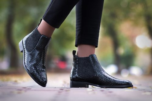   Жена отблизо's legs walking along the street in black python ankle boots.