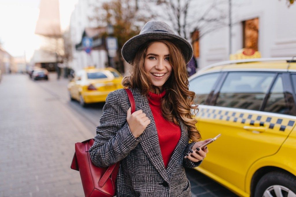 mulher com uma jaqueta de tweed em frente a um táxi