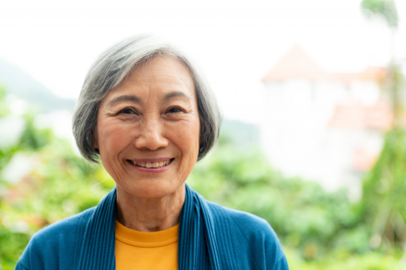   femme plus âgée aux cheveux gris souriant à l'extérieur