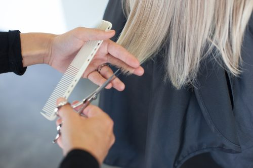  Primo piano di un parrucchiere che taglia una donna's gray hair.
