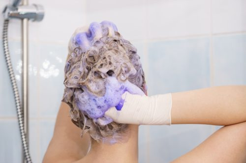   Femeie care folosește șampon violet