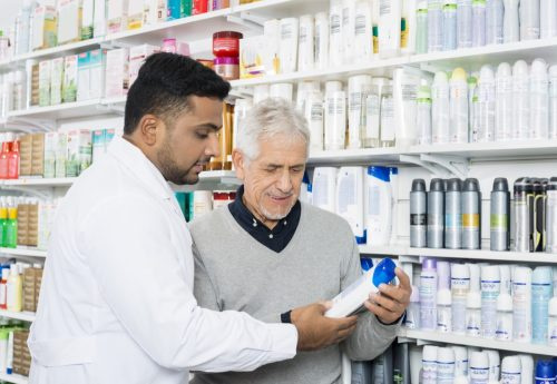   Apotheker hilft einem älteren Mann, Shampoo im Laden zu finden