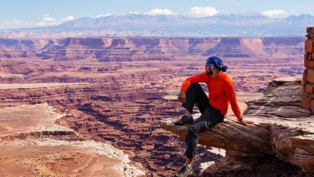   Turista sediaci na skalnom výbežku v národnom parku Canyonlands