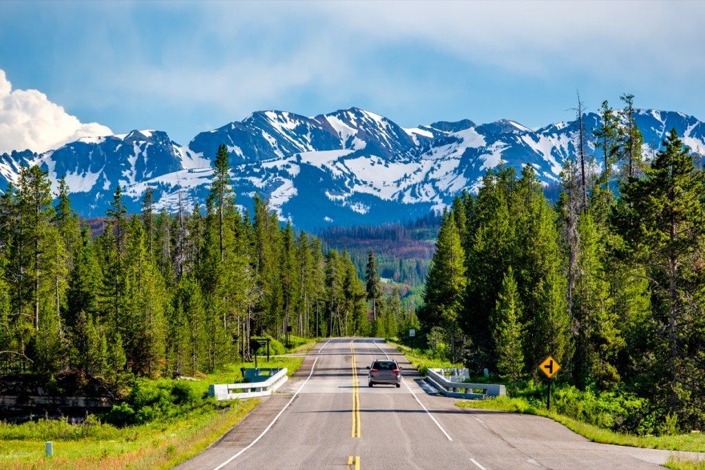 Jalan dari Taman Nasional Yellowstone ke Taman Nasional Grand Teton yang dipenuhi dengan pokok-pokok tinggi dan gunung-gunung yang diliputi salji di belakangnya, menyatakan fakta mengenai Wyoming