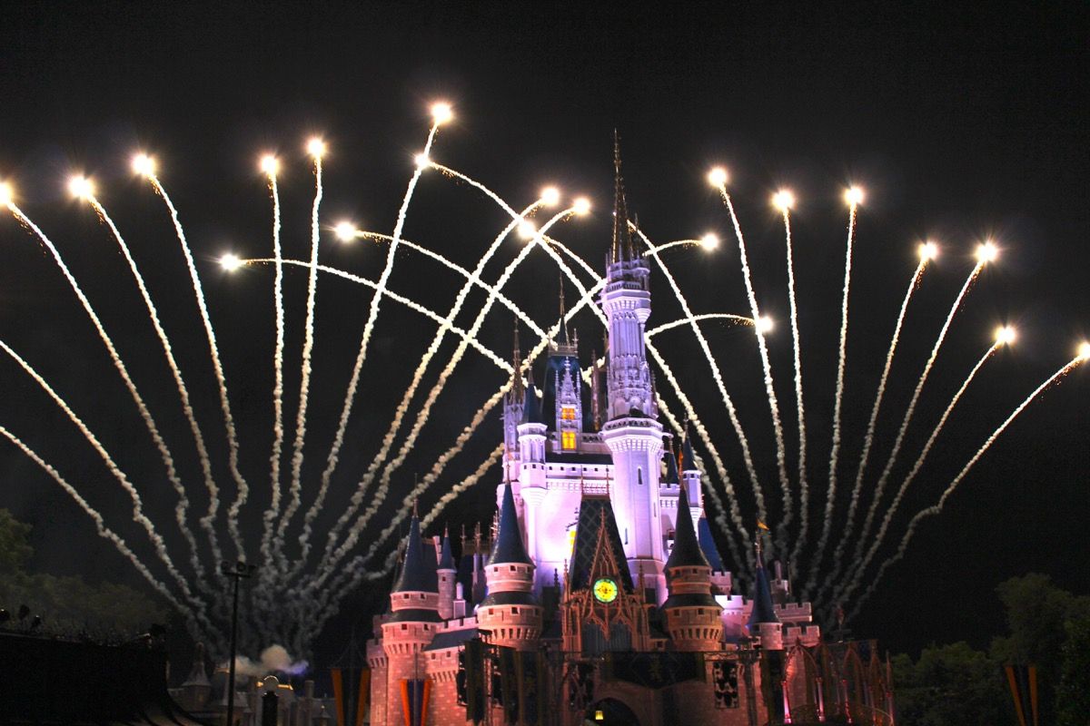 ปราสาทซินเดอเรลล่าสว่างไสวในยามค่ำคืนในอาณาจักรเวทมนตร์พร้อมดอกไม้ไฟเบื้องหลัง Disney Facts