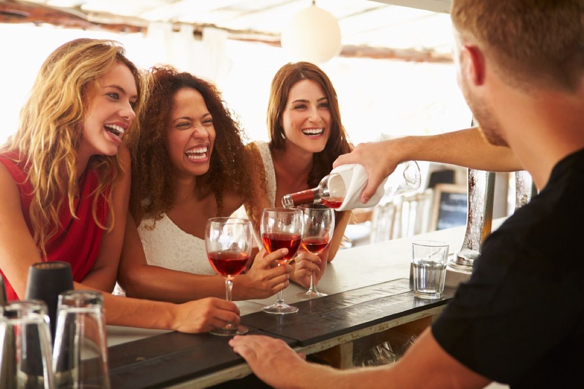 três mulheres com taças de vinho rindo juntas, amiga