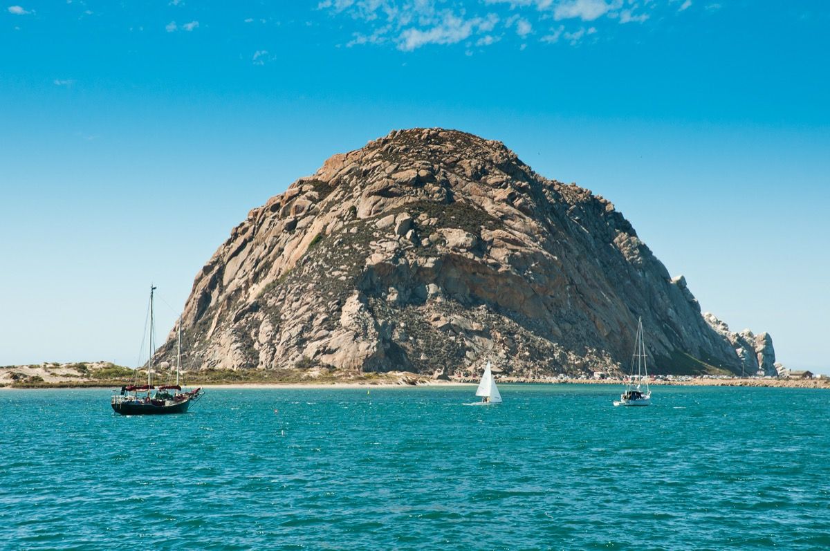 büyük bir kaya oluşumu ve yelkenli tekneleriyle morro bay california
