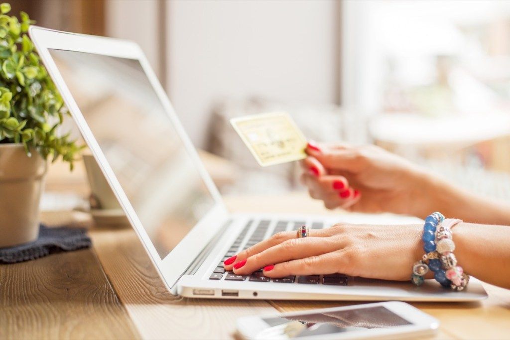 Mujer de compras online con un ordenador portátil y una tarjeta de crédito reservando vuelos baratos