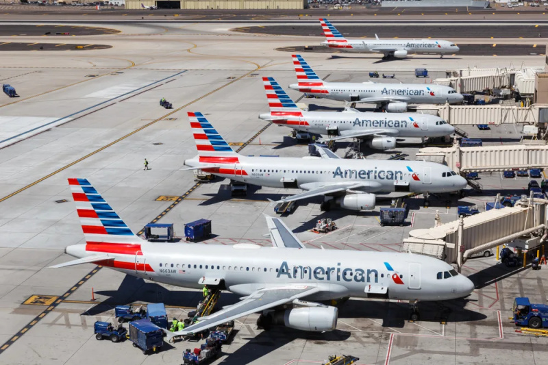   Пет самолета на American Airlines седят пред портите си и един самолет рулира на пистата на летище