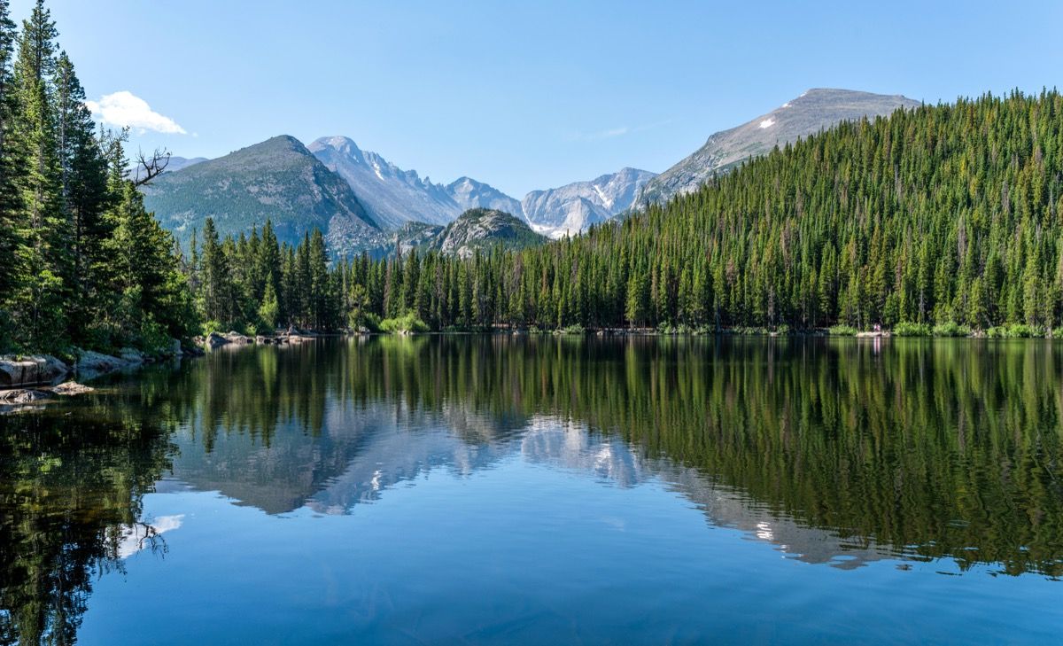 Longs Peak og Glacier Gorge reflekterer i blå Bear Lake på en rolig sommermorgen