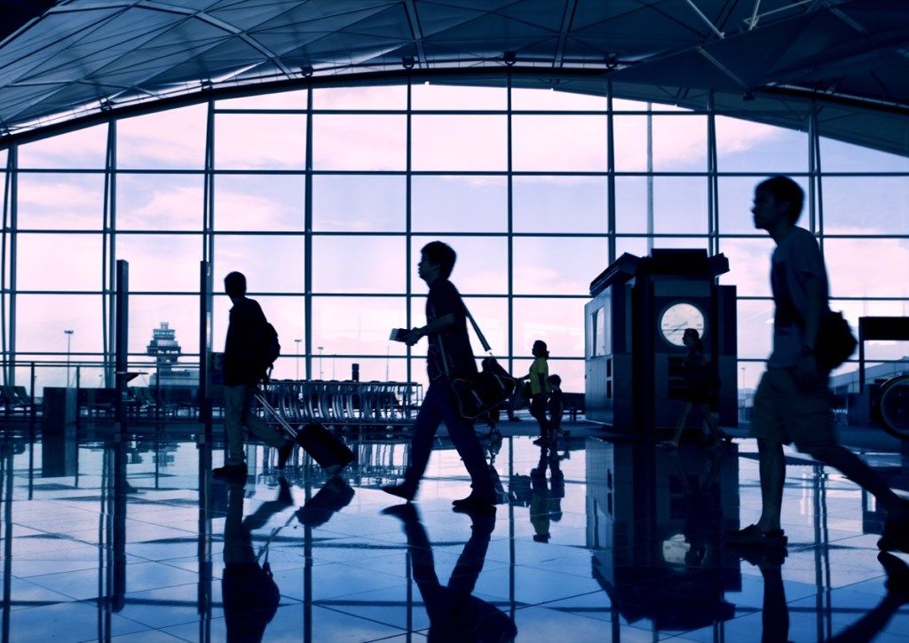 pasażerowie spacerujący po terminalu lotniska o zmierzchu