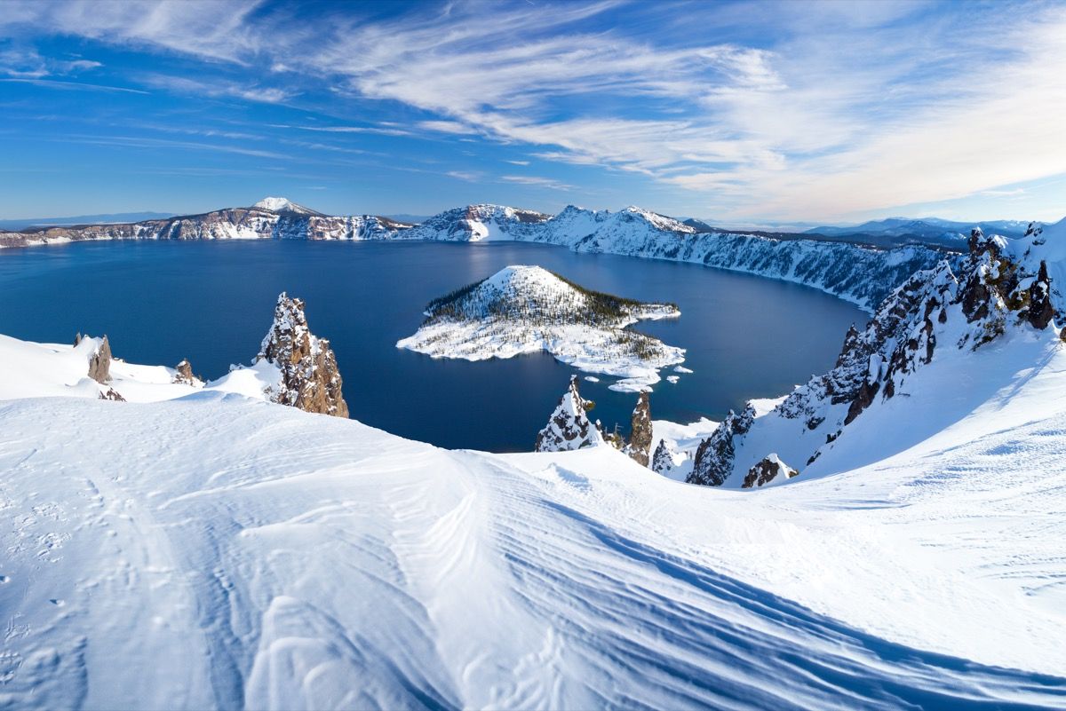 munți cu zăpadă care înconjoară un lac și o insulă