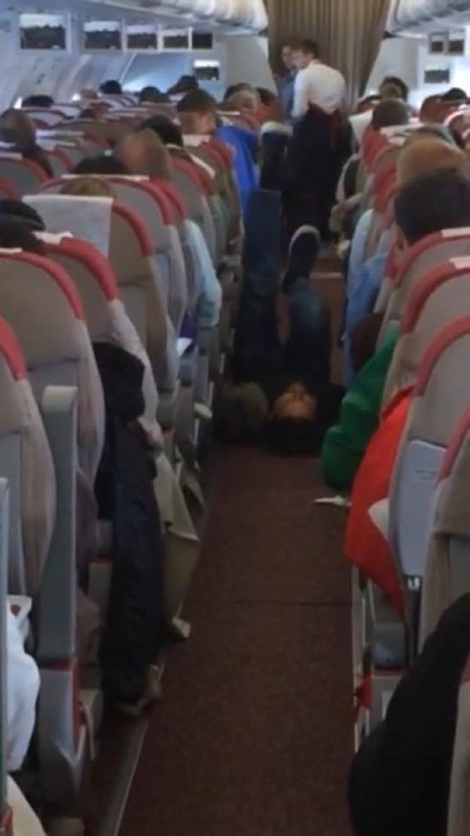 Mies työskentelee lentokoneen käytävän valokuvissa kauheista lentomatkustajista